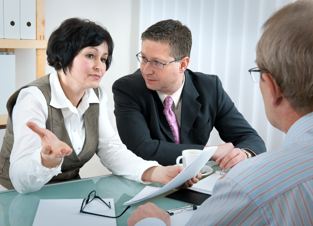 Woman and her lawyer in conversation with husband - Shutterstock