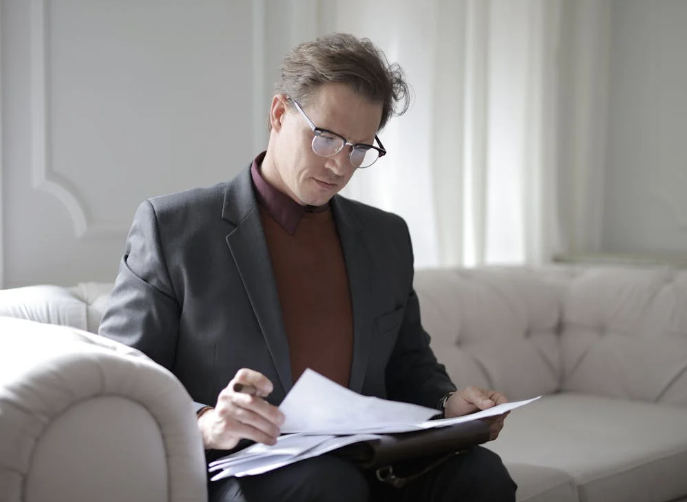 Classy executive male reading papers on couch